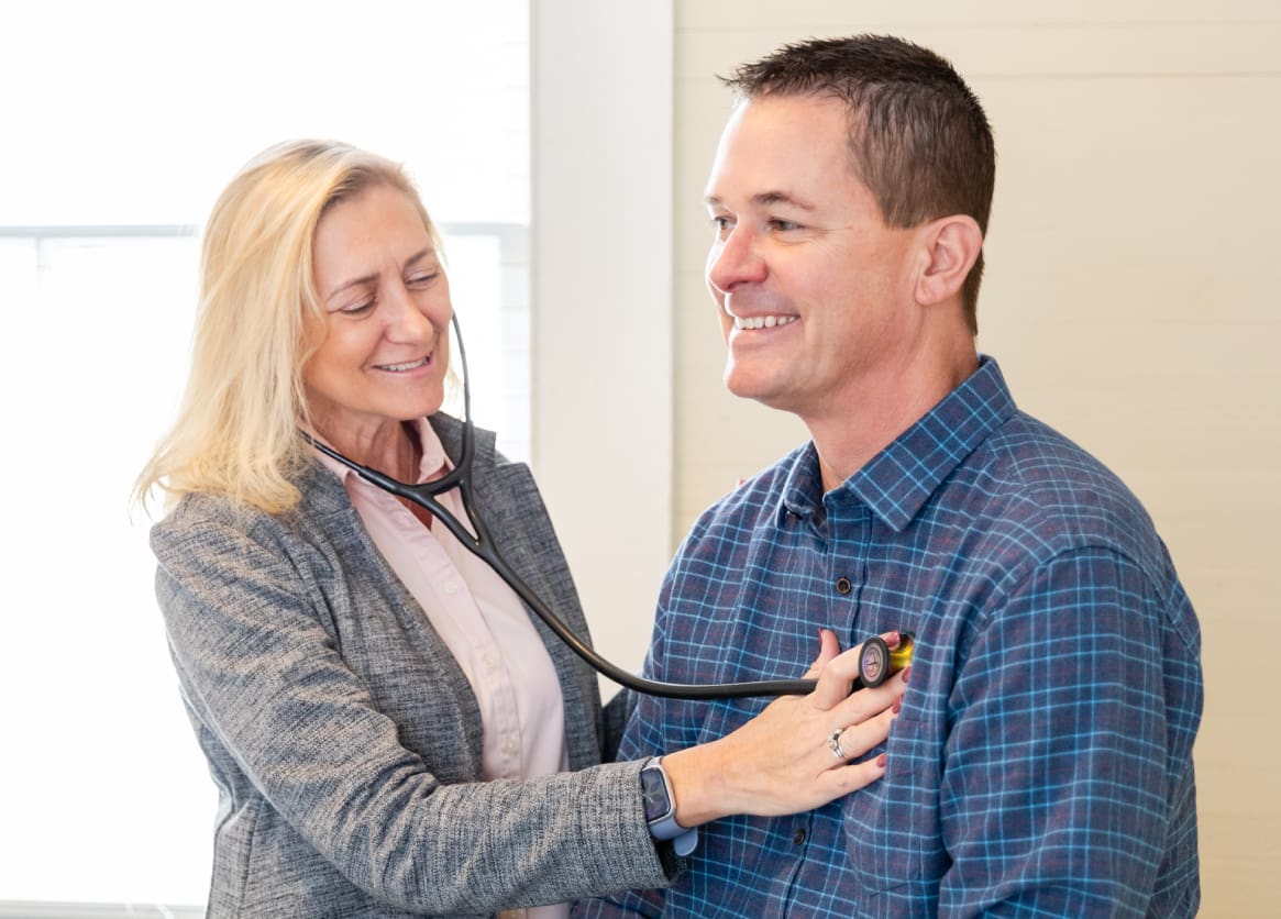 A woman is holding the stethoscope of a man.
