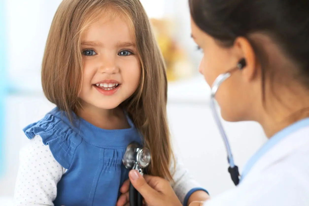 A little girl is being examined by a doctor.