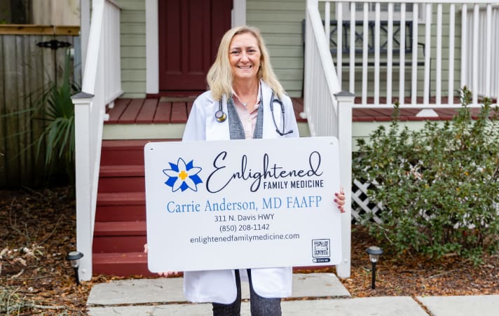 A woman holding up an advertisement for the enlightened family medicine.